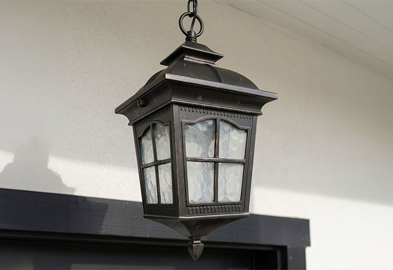 庭に吊り下げられたクラシックなランタン型屋外ペンダントライトが柔らかな光を灯している夜景