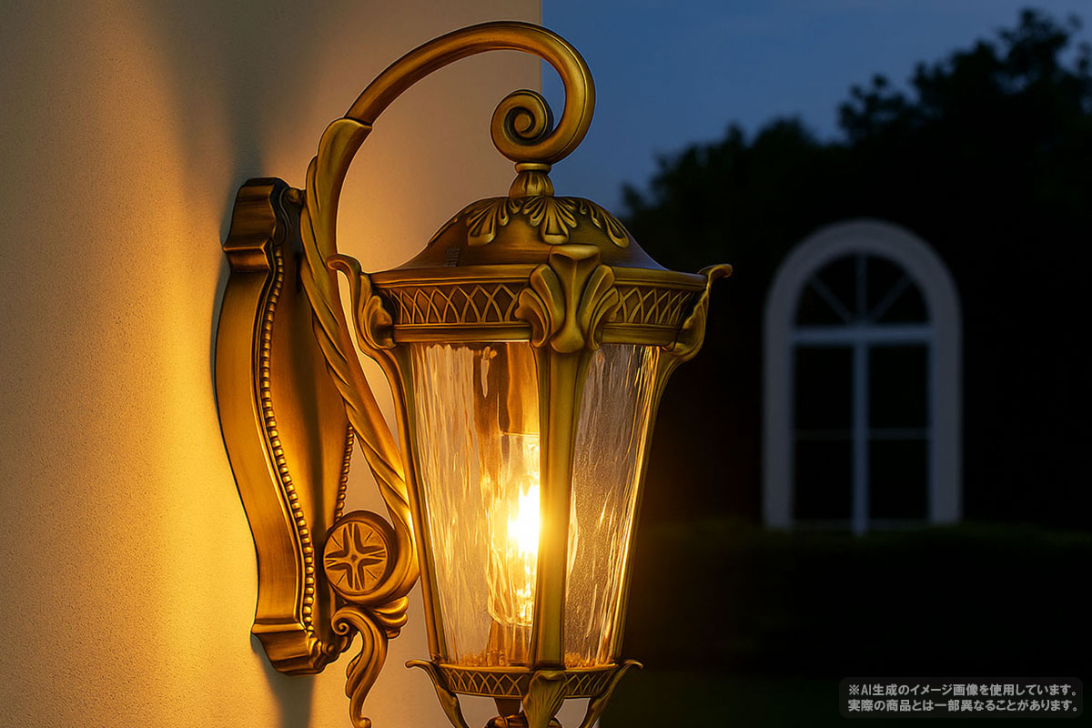 真鍮色の屋外用ブラケットライトが壁に取り付けられ、暖かく点灯している。











