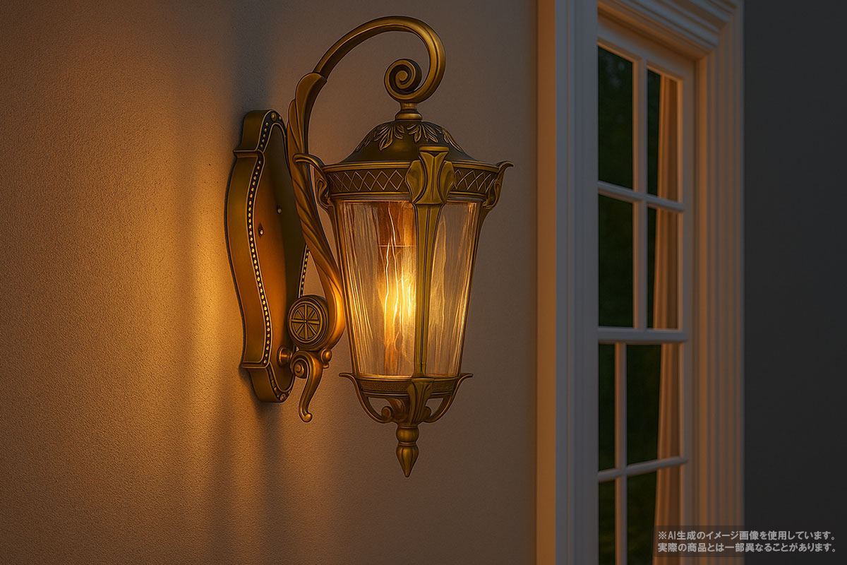 真鍮色の屋外用ブラケットライトが壁に取り付けられ、暖かく点灯している。











